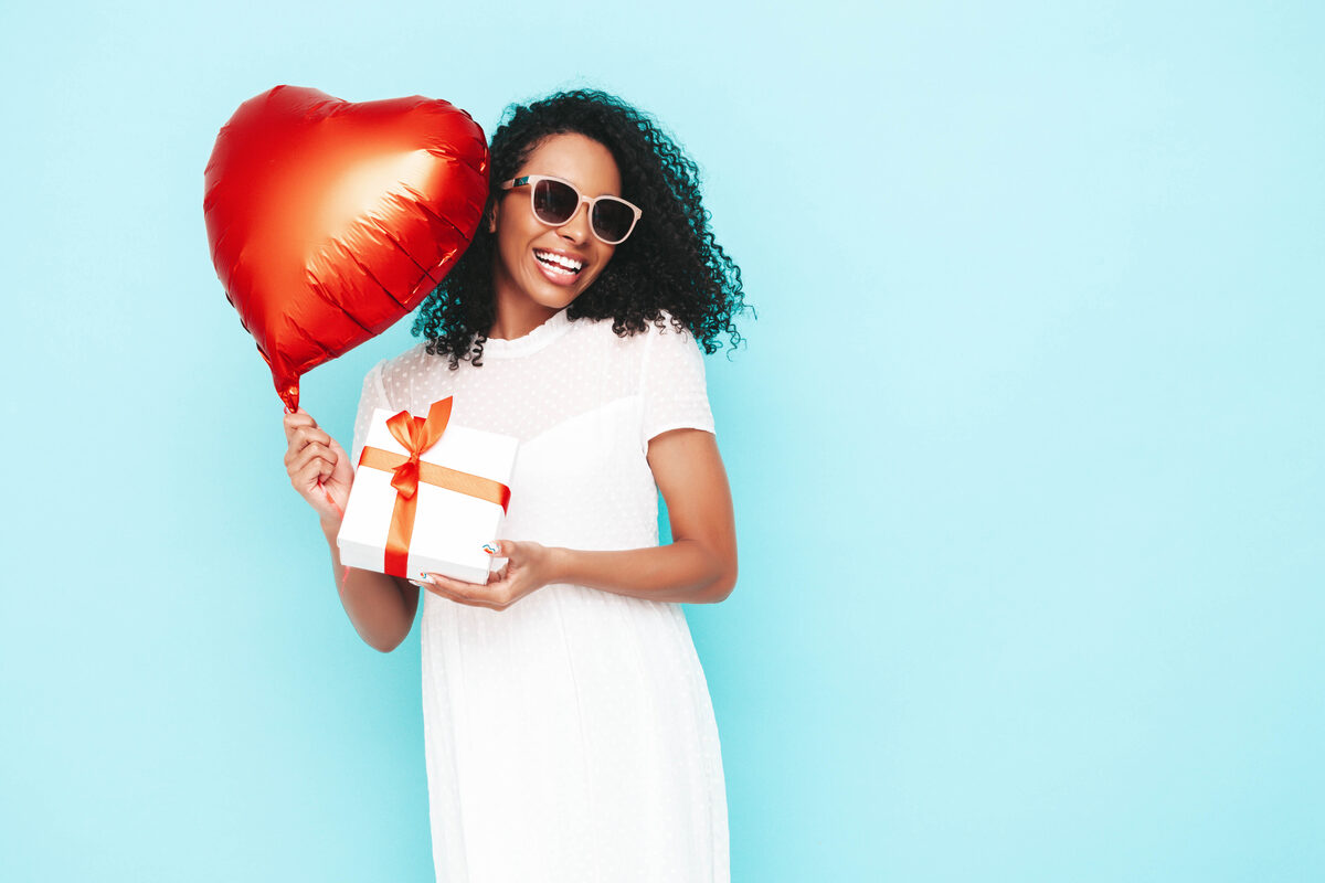 Woman smiling with a heart balloon and gift